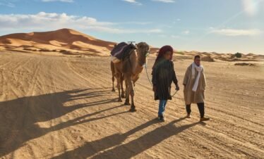 Marrakesh, Morocco - 31 December 2017: Camels and people going in desert